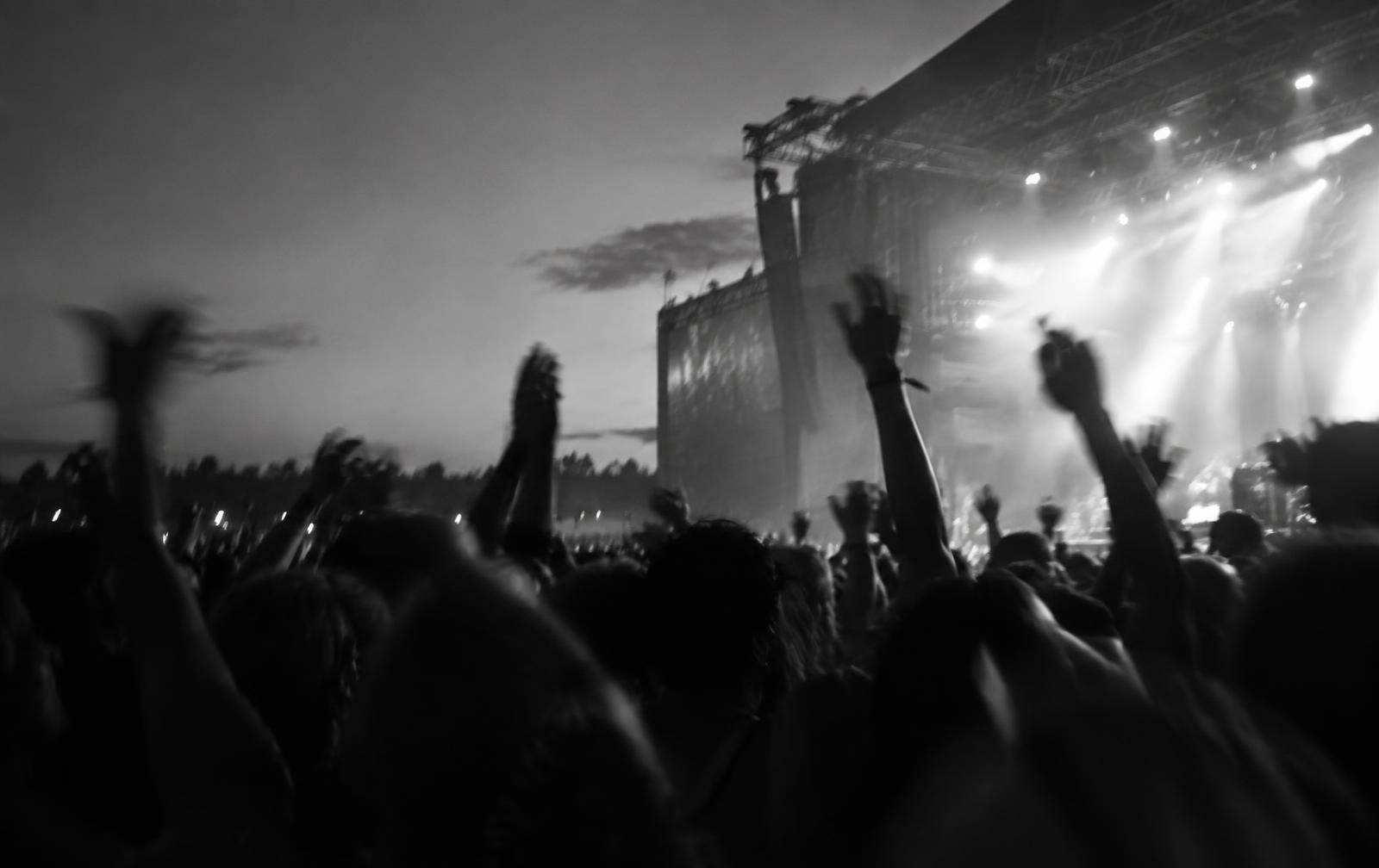 Festival crowd with raised hands under stage lights